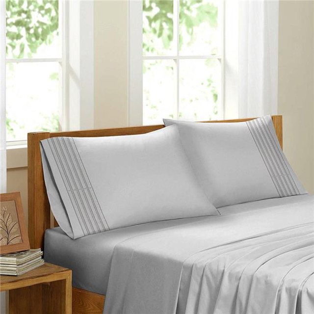 Egyptian Comfort Sateen Sheet Set, White - Queen. A luxurious white queen-size sheet set made from 100% brushed microfiber, featuring a silky soft texture, wrinkle resistance, and hypoallergenic properties. Includes a fitted sheet with 16-inch deep pockets, a flat sheet, and matching pillowcases. Displayed on a wooden bed frame in a bright, sunlit bedroom with a contemporary design.