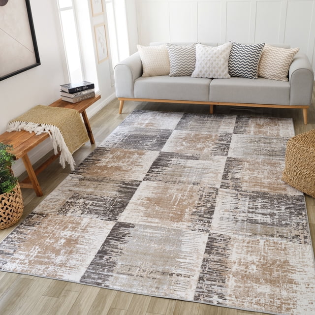 Rug Branch Cadence Abstract Indoor Area Rug in brown beige with a modern patchwork pattern, measuring 7'10" x 10'10", placed on light wood flooring in a living room featuring a light gray sofa with chevron and textured cushions, a wooden bench with a mustard throw, and woven natural decor accents.