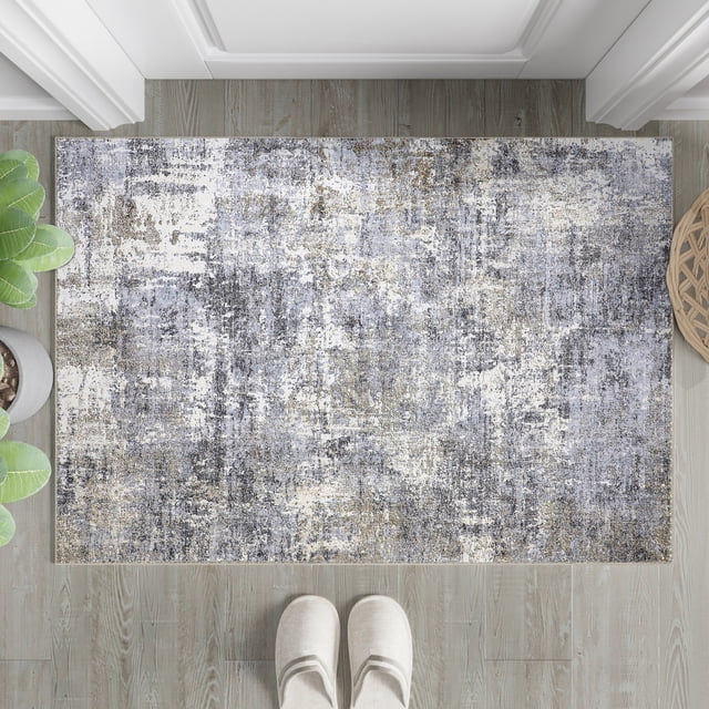 BERTHMEER 2'x3' Small Washable Abstract Area Rug in blue and gray tones, featuring a modern abstract design with a low-pile height of 0.2 inches. Made of polyester and thermoplastic rubber, this non-slip rug is shown placed in an entryway on a light wood floor, with slippers and a potted plant nearby. Suitable for indoor use in spaces like doorways, bathrooms, bedrooms, kitchens, and dorms. Machine washable and delivered in a folding package for convenience.