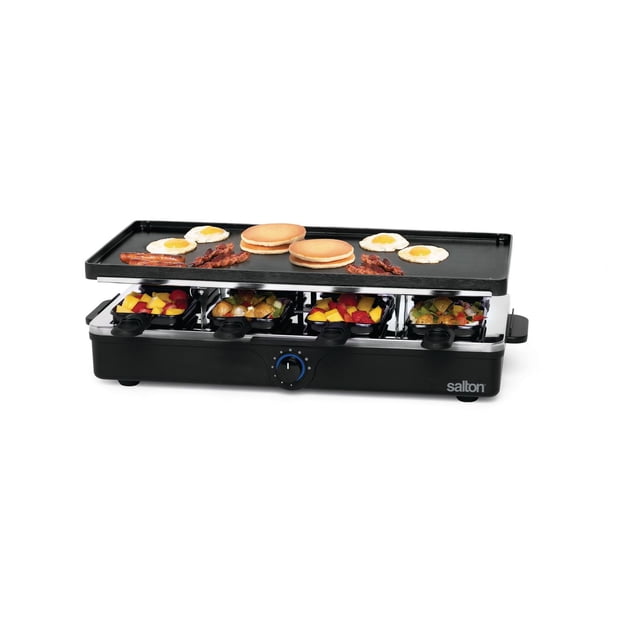 Salton Party Grill/Raclette, PG1645, with a black raised-edge grill plate cooking pancakes, fried eggs, bacon, and sausage on top, and eight non-stick color-coded raclette pans below filled with mixed vegetables and fruit, featuring adjustable temperature control, indicator light, stay-cool handles, and anti-slip feet on a black base with the Salton logo. It is also suitable for melting cheese and grilling fish, chicken, and sausage for group meals.