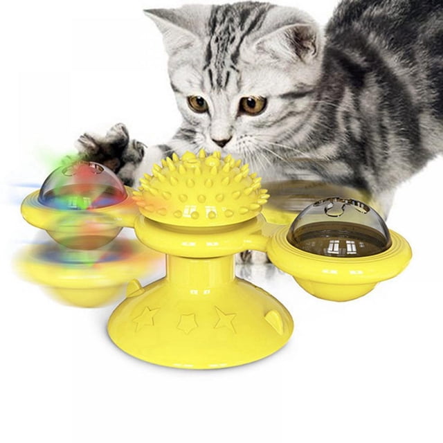 MesaSe Jouets Interactifs pour Chats d'Intérieur, un Jouet Moulin à Vent Jaune avec Deux Bacs Transparents pour Tenir des Balles d'Herbe à Chat, des Clochettes Ou des Balles Légères. le Centre Présente une Brosse de Rasage Douce pour Frotter le Visage, et le Jouet Tourne pour un Jeu Interactif. un Chat Tigré Gris Est Montré en Train de s'Engager avec le Jouet dans un Environnement Intérieur Douillet.