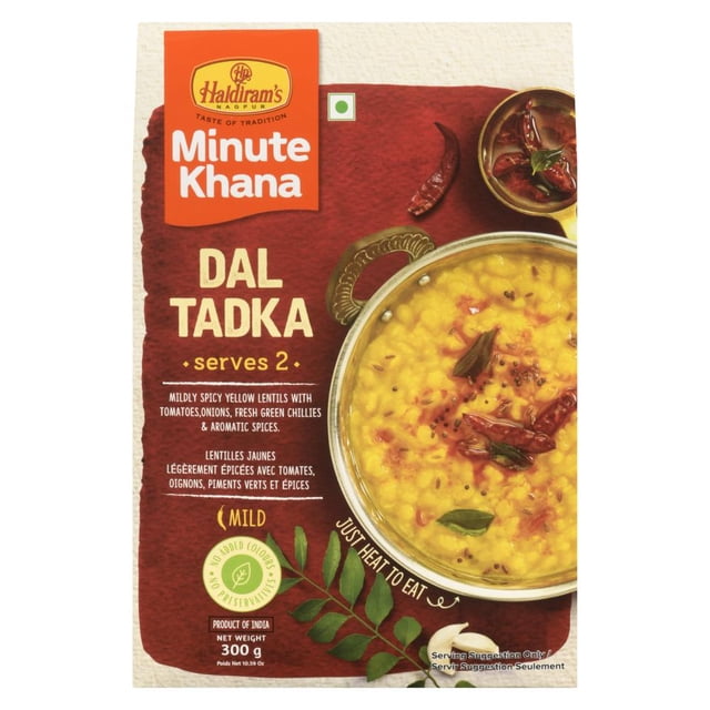 Haldiram RTE Dal Tadka package showing a mild spiced yellow lentil dish with tomatoes, onions, fresh green chillies, and aromatic spices in a brass bowl, serving two, ready to heat and eat as traditional Indian comfort food.