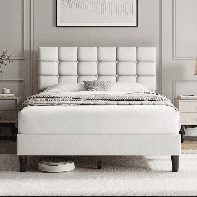 Fullfurnique Upholstered Platform Bed Frame with Square Tufted Headboard, Full, Beige, featuring a beige linen fabric headboard with deep square button tufting and foam padding. The bed frame includes sturdy wooden legs and 12 wooden slats supporting the mattress without a box spring. It offers 6-inch under-bed clearance where a robot vacuum is visible. The bed is styled with neutral bedding and light wood nightstands in a softly lit bedroom.