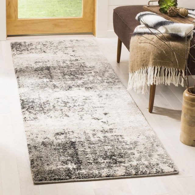 Safavieh Retro Corynn Abstract Area Rug runner with a low pile, featuring a mid-century modern abstract pattern in grey and cream tones, placed on light hardwood flooring near a wooden door and a brown bench with a beige fringed throw, suitable for enhancing hallway decor.