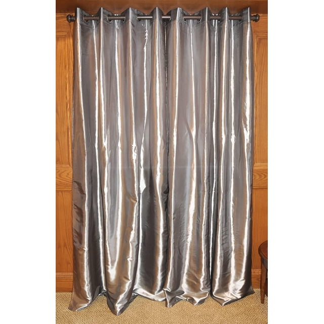 SUN TEXTILE CURTAIN en Taffetas à Oeillets en Argent Métallique, Suspendu à une Tige Métallique Foncée avec des Embouts Ronds. Ce Panneau de 55 par 84 Pouces Présente un Tissu Taffetas Texturé et Réfléchissant la Lumière avec une Finition Métallique Brillante des Deux Côtés. Conçu pour Filtrer la Lumière sur les Couvre-Fenêtres, Il Est Montré Entièrement Étendu contre les Murs en Panneaux de Bois et un Plancher de Tapis à Motifs. le CURTAIN Convient Aussi pour Ajouter une Touche Métallique Moderne aux Intérieurs de la Maison.