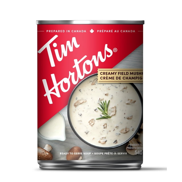Soupe Crémeuse aux Champignons par Tim Hortons en Conserve Rouge et Argentée Présentant une Vue de Haut en Bas d'Un Bol de Soupe Crémeuse aux Champignons avec des Morceaux de Champignon et une Garniture de Romarin, Sertie sur une surface Boisée Légère avec des Champignons Entiers et une Petite Pichet à Crème, Soupe en Conserve Prête à Servir Préparée au Canada, Idéale pour des Repas Pratiques au Garde-Manger.