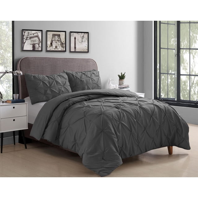 Swift Home Pintuck Comforter Set in grey microfiber fabric with textured pintuck pleats on comforter and matching pillow shams, displayed on a bed with a curved upholstered headboard in a modern bedroom with light wood flooring, white walls, black-framed windows, and framed cityscape artwork, suitable for year-round use and easy machine care.