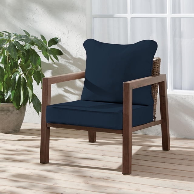 HOMETRENDS Coussin de Siège Profond de Luxe Bleu Marine sur une Chaise d'Extérieur en Bois avec Dossier Tressé, Installé sur un Plancher de patio en Bois Clair à Côté d'Une Plante Verte en Pot et d'Un Mur en Stuc Blanc avec Fenêtre, Doté d'Un Tissu Traité aux UV, Résistant à la Décoloration et Hydrofuge Idéal pour une Utilisation Extérieure et un Nettoyage Facile.