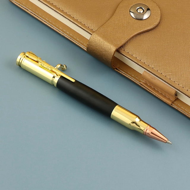 Stylo à Bille en Bois, Stylo Anti-Stress, Cadeau Amusant 1 ml. un Stylo Élégant avec un Corps en Bois Noir, des accents Dorés et une Pointe Ton Cuivre, Conçu pour l'Écriture et le Soulagement du stress. le Stylo Est Placé sur une surface Bleue à Côté d'Un Carnet en Cuir Beige avec Fermoir à Bouton.