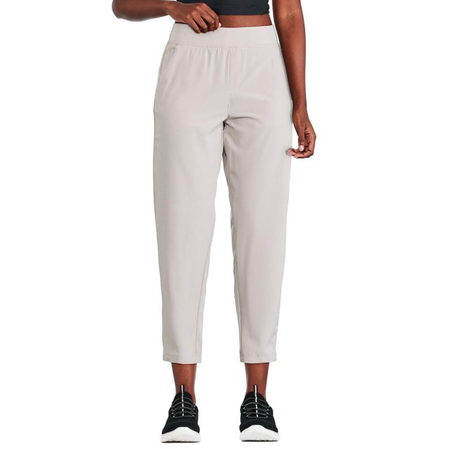 Athletic Works Pantalon pour Femme à Bas Ouvert en beige Pâle Montré Orienté vers l'Avant sur un Modèle de la Taille aux Chevilles, Fabriqué en Tissu Tissé Extensible, avec une Grand Ceinture Élastiquée, Coupe Décontractée, Deux Poches Latérales à Cordon, et des Panneaux Latéraux à Blocs de Couleur, Assorti aux Chaussures de Sport Noires.