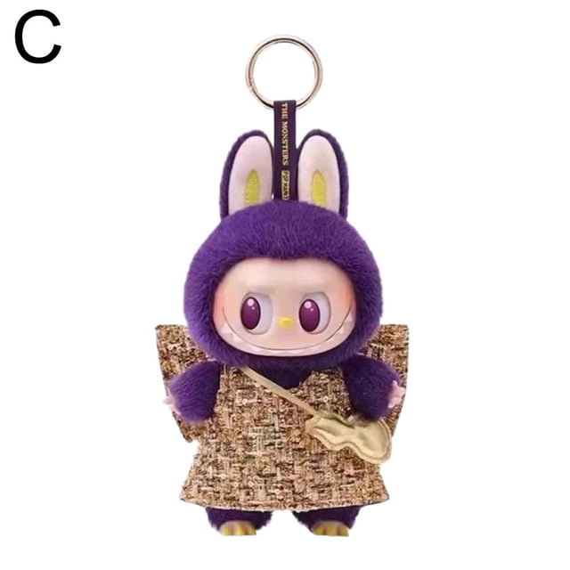 Limited Edition Plush Toy in sky blue, brown, and purple, measuring 17cm (6.63 inches). The toy features a unique design with a purple plush exterior, bunny ears, and a resin face with expressive eyes. It is dressed in a textured brown outfit with a small gold bag and includes a keyring attachment for portability. Made from high-quality plush and resin materials, this collectible toy is eco-friendly and designed for durability.