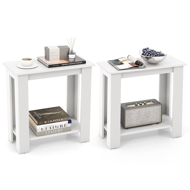 Gymax 2 PCS 2-Tier End Table Modern Sofa Bedside Compact Nightstand with Storage Shelf in white. The set includes two rectangular tables with a wide tabletop and a bottom shelf for storage. Each table features four sturdy legs with anti-slip foot pads and a compact design suitable for small spaces. The tables are styled with books, a cup, a bowl, and decorative items, showcasing their versatile use as nightstands or sofa side tables.