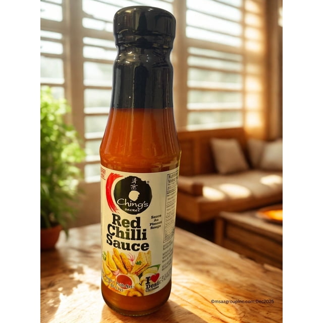 Une Bouteille de 170 ml de SAUCE au Piment Rouge de Qualité Supérieure CHING'S, une SAUCE Piquante de style Indo-Chinois. la Bouteille Présente un Bouchon Noir et une Étiquette avec des accents Rouges et Blancs Vibrants, Mettant en Valeur le logo Secret de CHING'S et une image d'Aliments comme des Rouleaux de Printemps et des Nouilles. la SAUCE Est Faite avec des Piments Rouges, de l'Ail et du Gingembre, Offrant une Saveur Audacieuse et Épicée. la Bouteille Est Placée sur une table en Bois
