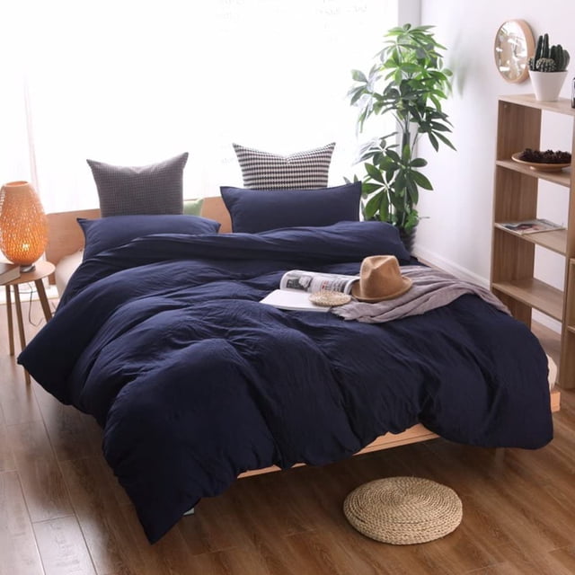 3 Piece Solid Color Purplish Blue Quilt Cover Bedding Duvet Cover Set (Queen) displayed in a cozy bedroom setting. The set includes a purplish blue duvet cover measuring 228x228 cm (90x90 inches) and two matching pillowcases measuring 51x70 cm (20x28 inches). Made from hypoallergenic microfiber, it is lightweight at 1.2 kg (2.6 lb) and machine washable for easy care. The bedding is styled on a wooden bed frame with decorative pillows and natural lighting, creating a warm and inviting atmosphere.