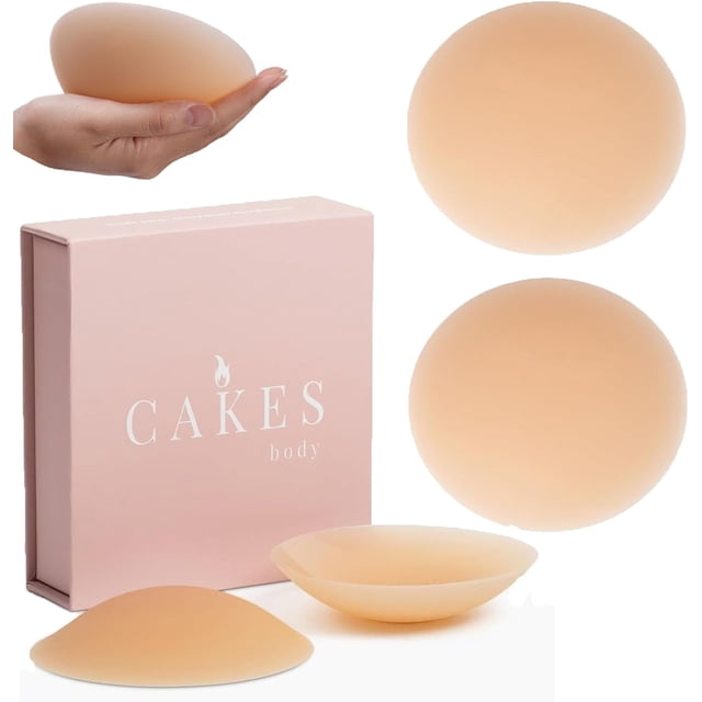 Cakes Housses Adhérentes Sans Coutures, Couvre-Tétons en silicone Sans Coutures Conçus pour Femmes, Présentés sous une Forme Ronde avec une Couleur Ton Peau. Comprend une Paire de Housses Réutilisables, Imperméables et Lavables Exposées aux Côtés d'Une Boîte Rose de Marque Étiquetée « Cakes body ». les Housses Offrent une Couverture Invisible et Anti-Lumière et Conviennent aux Tailles de Bonnets A-C. Idéal pour un Confort et une Confiance Toute la Journée.
