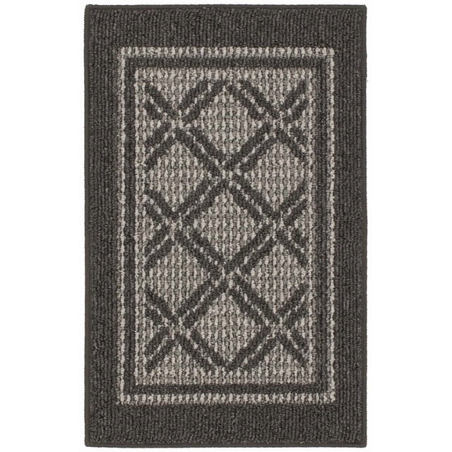 Hometrends Shefield Polyester Accent Rug with black borders and a grey geometric diamond lattice pattern. Tufted olefin yarn construction offers moisture, stain, and fade resistance, ideal for kitchens, entryways, and laundry rooms. Its low-profile pile reduces door obstruction and is easy to clean.
