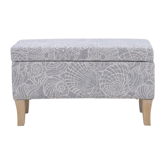 Sydney Stone Storage Ottoman featuring a large-scale coastal shell pattern in soft grey hues, cushioned upholstered top, and solid wood legs in rustic grey finish, offering versatile storage and seating suitable for living room or entryway.