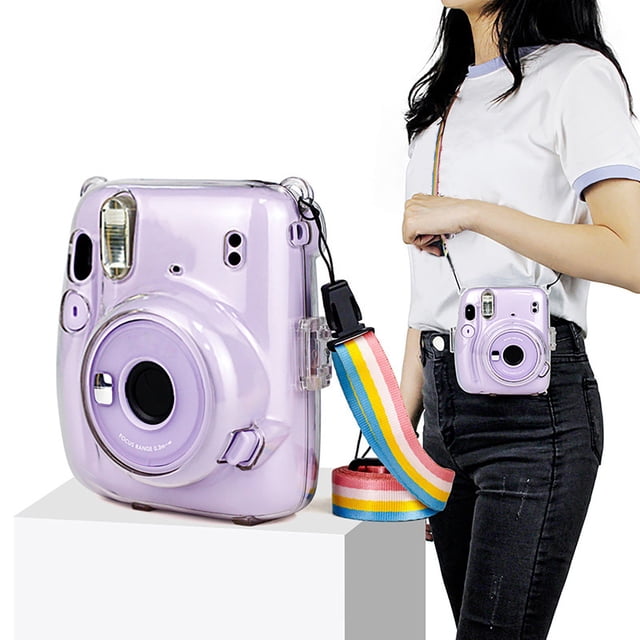 TIMIFIS Étui Protecteur Transparent pour Appareil Photo Instantané Instax Mini 11, avec un design d'Une Clarté Cristalline et une Bandoulière Arc-en-Ciel. l'Étui Résistant aux Chutes Protège l'Appareil Photo de la Poussière, des Égratignures et des Dommages. une Personne Est Montrée Portant l'Appareil Photo avec la Sangle Ajustable, Mettant en Valeur Sa Portabilité et Sa Convenance pour une Utilisation Intérieure et Extérieure.