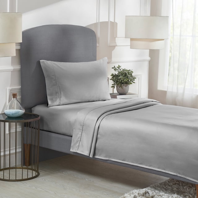 California Design Den Sheet Sets, Natural 100% Cotton Sheets, Soft Luxury 400 Thread Count Sateen Bedding Sheets Set with deep pocket cooling sheets displayed on a neatly made bed. The set includes a fitted sheet, flat sheet, and pillowcase in a light grey colour, showcasing a smooth and silky sateen weave. The bed is styled in a modern bedroom with neutral decor, featuring a grey upholstered headboard, a side table with decorative items, and soft natural lighting.