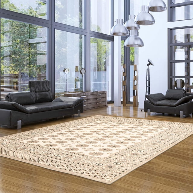 Tekke Oriental Area Rug for Living Room, Dining Room, Bedroom displayed on a polished wooden floor in a modern living room with large windows. The beige rug features symmetrical oval and diamond-shaped motifs in a traditional Oriental pattern, placed between two black leather sofas. Its soft pile and classic design also make it suitable as an accent piece in bedrooms or dining rooms.