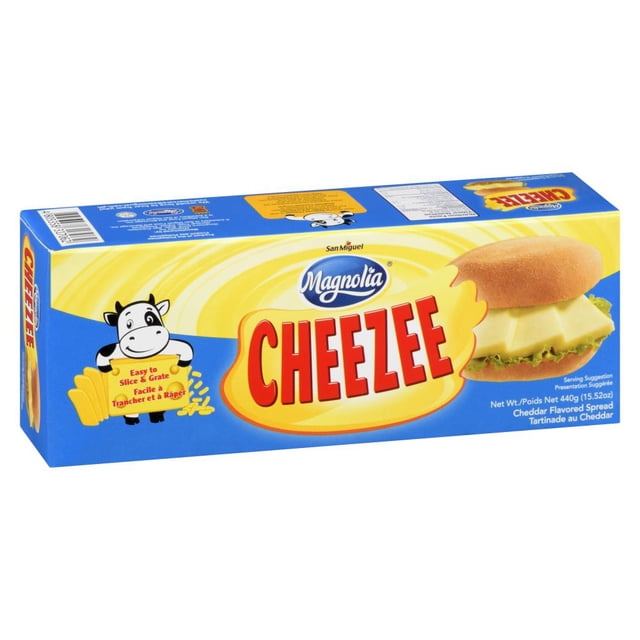 Magnolia Cheezee Block packaging in a blue and yellow rectangular box with the Magnolia logo and bold red Cheezee text, featuring a cartoon cow holding a sign that reads Easy to Slice & Grate, and a sandwich image with cheddar-flavored spread on lettuce inside a bun, suitable for spreading and melting in meals.