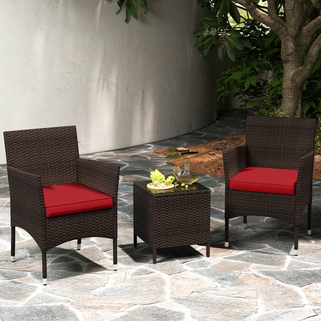 Costway Ensemble de Conversation Extérieur 3 Pcs avec Siège Coussiné et Plateau en Verre Trempé Rouge, Comprenant Deux Chaises en Rotin PE Brun Mélangé avec des contours Ergonomiques et des Coussins Rouges, Assorti à une table Basse Carrée avec Dessus en Verre Trempé. Idéal pour Meubles de patio Ou Sièges Extérieurs, l'Ensemble Est Exposé sur un patio en Pierre Entouré de Verdure.