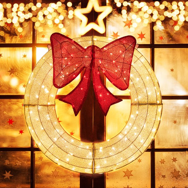 Costway 48 Inch Pre-Lit Christmas Wreath with 200 LED Lights, featuring a large red bow and warm white lights, displayed on a window with festive star decorations. The wreath is crafted from weatherproof materials with a sturdy metal frame, suitable for indoor and outdoor use. Includes two hanging hooks for easy installation.