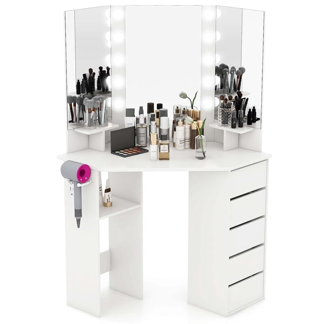 Costway Coiffeuse d'Angle Station de Coiffeuse Cosmétique avec Miroir DEL et Prises de Courant en Blanc. Cette Coiffeuse d'Angle Gain de Place Comprend un Miroir DEL à Trois Volets avec Luminosité Réglable et Trois Réglages de Couleur, un Grand Dessus de Table, Deux Tablettes Supérieures, une Tablette Inférieure et Cinq Tiroirs pour un Grand Rangement. Comprend un Support Latéral pour Séchoir à Cheveux et une Station de Recharge Intégrée avec Deux Prises CA, un port USB et un port Type‐C. Fabriquée en Bois d'Ingénierie et en MDF avec Patins Antidérapants pour la Stabilité.