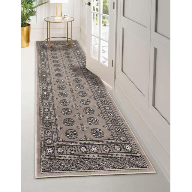 ECARPET Traditional Area Rug in grey featuring a classic oriental Bokhara geometric pattern with symmetrical motifs and a detailed border, placed in a white hallway by a glass-paneled door with a gold round side table and gold planter. Suitable for high-traffic and pet-friendly spaces.