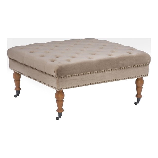 Linon Isabelle Square Tufted Upholstered Ottoman with wood legs in soft tan fabric. Features a tufted top, antique brass nailhead accents, and turned dark walnut legs with metal casters. Measures 34.625 inches wide, 34.625 inches deep, and 17.72 inches high. Chic square design suitable for use as an ottoman or coffee table, often used to complement living room seating arrangements.