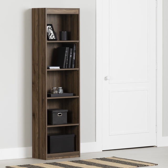 South Shore Axess 5-Shelf Narrow Bookcase in natural walnut finish with five open compartments, including adjustable shelves holding books, decorative jars, and storage boxes, placed against a light grey wall next to a white door, suitable for small rooms and versatile storage needs.