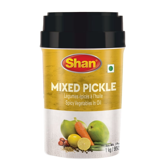 Shan Mixed Pickle 1kg jar containing mango, carrot, lime, and chilies preserved in tangy, spicy mustard oil, with a yellow and white label and black lid, suitable for enhancing pantry condiments and adding bold flavor to meals.
