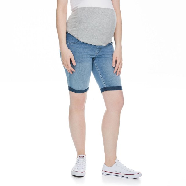 Pregnant woman modeling Paisley Sky maternity jegging Bermuda shorts in light blue denim with rolled cuffs, paired with white sneakers.