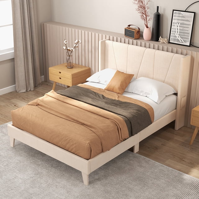 Costway Full Size Upholstered Bed Frame with Elastic Pockets Mattress Foundation in beige, featuring a 42-inch high wingback headboard upholstered in breathable linen fabric. The bed frame includes two elastic side pockets for storing small items like remotes or glasses and offers a 6.5-inch under-bed clearance for additional storage. Designed with a sturdy structure, it supports up to 660 lbs and includes thick slats, extra metal legs, and adjustable foot pads for stability. The platform bed eliminates the need for a box spring and accommodates mattresses 8 to 12 inches thick. Displayed in a modern bedroom setting with wooden side tables and neutral decor.