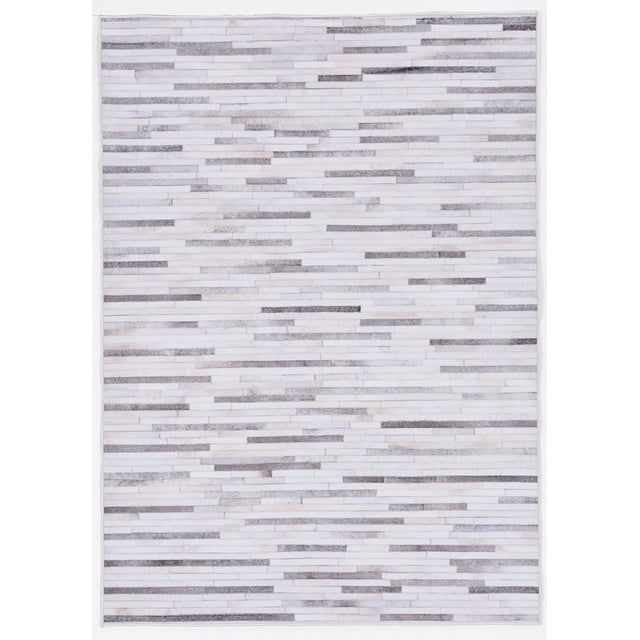 Laredo Tanner Grey & Ivory 5' x 7' area rug with a digitally printed low pile patchwork cowhide design in grey, ivory, and neutral tones, featuring serged edges, subtle shine, and a felt backing with rubber gripper dots to prevent slipping, ideal for defining spaces or high traffic areas.