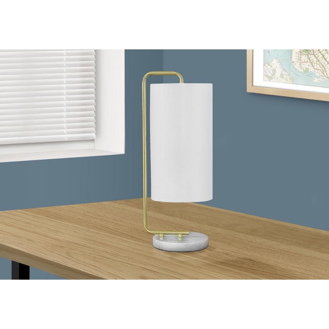 Monarch Specialties Lighting 20"h table lamp with a white marble base and slim gold metal arm holding a cylindrical ivory fabric shade, placed on a light wood desk against a blue wall near a window with white blinds and a framed map, suitable for modern living spaces.