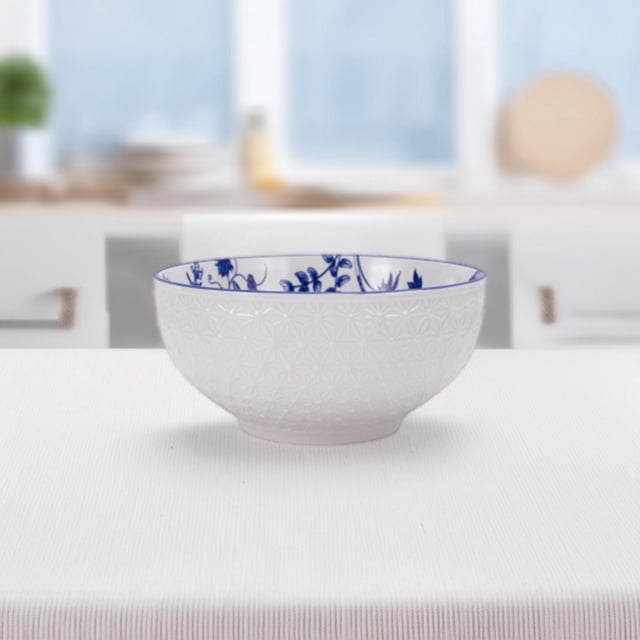 Mainstays 8.25" pad printed big bowl with white embossed geometric exterior and blue floral interior, made of durable stoneware, ideal for salads or daily meals, displayed on a white textured tablecloth in a bright kitchen.