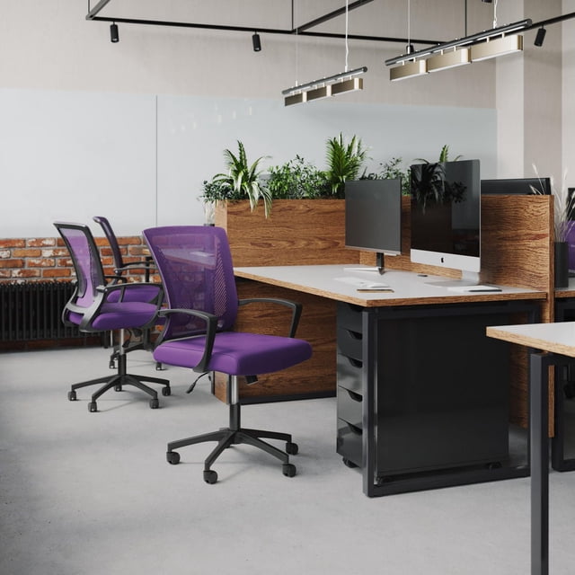CorLiving Cooper ergonomic mesh back adjustable height adult office chair with wheels in purple fabric, shown in a modern office with wood and black metal desks, dual computer monitors, and planter dividers with green plants.