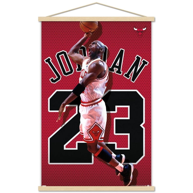 Michael Jordan - Jersey Wall Poster, 22.375" x 34" Framed showing Michael Jordan in a white Chicago Bulls basketball uniform with number 23, jumping mid-air with a basketball against a red mesh background featuring large black and white number 23 and the name JORDAN in bold letters, with the Chicago Bulls logo in the top right corner, ideal for sports-themed room decor.