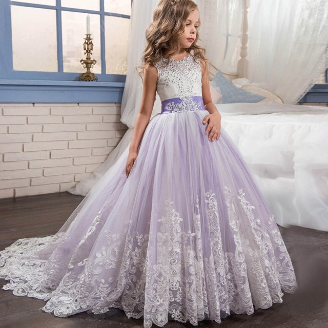 LSLJS Girls Embroidery Princess Dress Wedding Birthday Party Long Tail Prom Gowns Dresses. This sleeveless dress features a soft polyester and tulle mesh construction with an embroidered floral design, lace skirt yarn, and a hidden back zipper. The long tail gown has a multi-layered tulle skirt with intricate lace detailing, a fitted bodice, and a satin tie at the back. Shown in a pastel lavender and white color combination, it is suitable for weddings, birthday parties, pageants, and other formal occasions. The dress is displayed in a cozy, elegant room with a bed and window in the background.