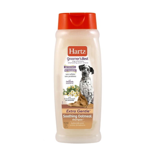 Hartz Groomer's Best Oatmeal Dog Shampoo 532ml bottle with orange flip-top cap, featuring a label with a black and white spotted dog wrapped in a brown towel, chamomile flowers, and text highlighting no sulfates, no parabens, chamomile essential oil, extra gentle soothing oatmeal formula, and buttermilk scent, suitable for dogs with sensitive skin.