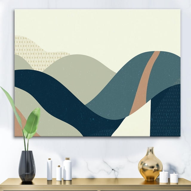 Designart Abstract Geometric Landscape With Hills Canvas Wall Art depicting layered abstract hills in muted blue, beige, and tan with subtle geometric patterns, printed on premium cotton canvas and gallery-wrapped with design extending on sides, ready to hang above a modern console table with decorative vases.
