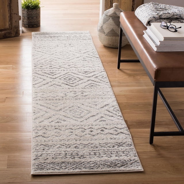 SAFAVIEH Tulum Merletta Tapis Géométrique Marocain 2'x8' Coureur Présentant des Fils Synthétiques Doux dans des Tons Neutres Clairs avec des Motifs Géométriques Marocains, Posé sur un Plancher de Bois Clair à Côté d'Un Banc en Cuir Brun avec des Livres, des Lunettes et une Couverture Pliée, Près d'Un Panier Tressé et d'Une Plante en Pot, Idéal pour Rehausser le décor du Couloir Ou de l'Entrée.
