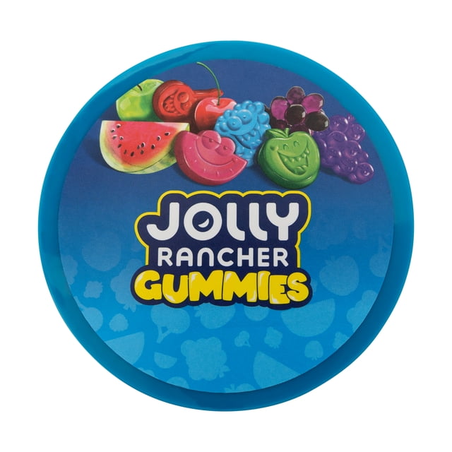 Jolly Rancher Gommes Couvercle de Contenant Circulaire Bleu Mettant en Vedette des Formes Colorées de Fruits Gélifiés Incluant Melon d'Eau, Cerise, Framboise, Pomme Verte et Raisin au-Dessus du logo Jolly Rancher Gommes en Blanc et Jaune sur Fond Bleu avec de Subtils Motifs de Fruits.