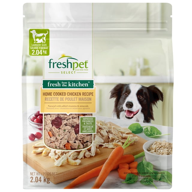 Freshpet Fresh Dog Food, Fresh From The Kitchen, Home Cooked Chicken Recipe, 2.04 Kg resealable bag featuring farm-raised shredded chicken, antioxidant-rich cranberries, fresh carrots, and spinach on a wooden cutting board with a happy black and white dog in a bright kitchen.