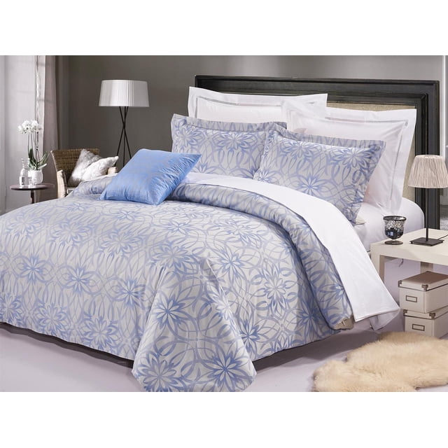 Johnson Home 200 TC Fashion Bedding Cotton Yarn Duvet Cover Sets (Queen) with a beige and blue floral geometric pattern on the duvet cover and pillow shams, paired with white sheets and a solid blue accent pillow. Displayed in a modern bedroom featuring a black headboard, side table with lamp, wicker chair, and beige rug. The breathable cotton fabric provides softness and temperature regulation for comfortable year-round use.