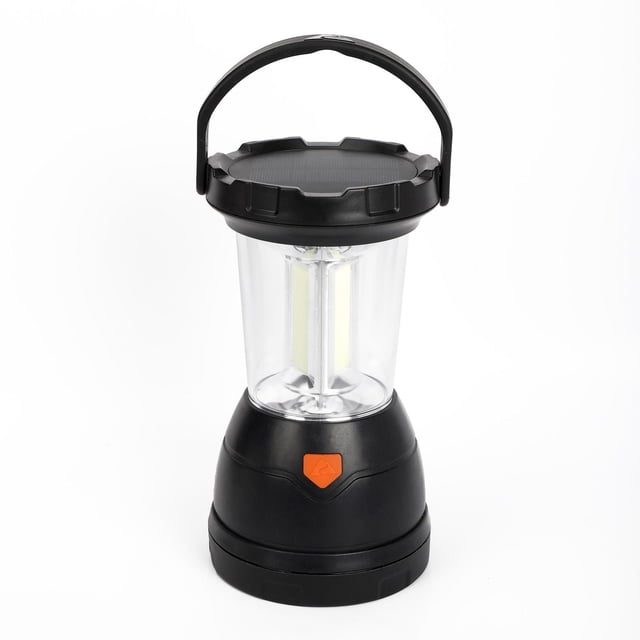 Ozark Trail Triplex LED Survival Lantern, 800 lumens, with a black base and clear light chamber housing adjustable LED bulbs, topped with a solar panel and black carrying handle, featuring an orange power button, rechargeable via USB, solar, or crank, ideal for camping and emergency lighting.