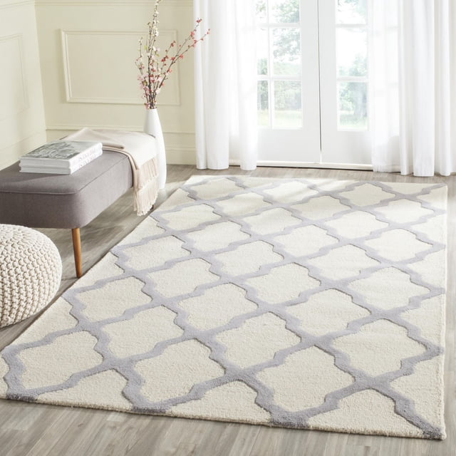 Safavieh Cambridge Liam Tapis Géométrique pour Aire sur Plancher de Bois Clair dans une Pièce Lumineuse, Présentant de la Laine Tuftée à la Main avec une base Crème et un Motif de Treillis Géométrique Gris Pâle, Style avec un Banc Gris, un pouf Tricoté et un vase Blanc avec des Fleurs Près de Rideaux Transparents et des Portes en Verre, Idéal pour la Déco Moderne de la Maison Ou du Bureau.
