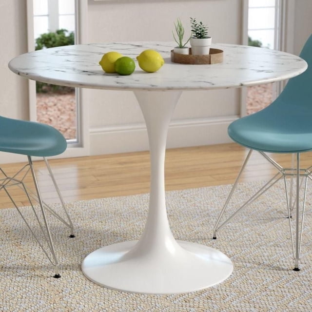 Lux Faux Marble table in White Stone Finish, round dining table with a faux marble stone top and white stainless steel pedestal base, 29 inches high by 36 inches wide, set on a beige textured rug with two blue modern chairs, decorated with lemons, a lime, and small potted plants on a wooden tray in a bright room with large windows, ideal for living room, entryway, or dining room.