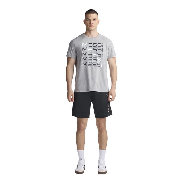 Messi Men’s Short Sleeve Tee in grey featuring repeated black and white Messi logo text on the front, paired with black shorts with a vertical Messi logo on the left leg, white crew socks, and white sneakers with black stripes, shown in a centered front-facing full-body view.